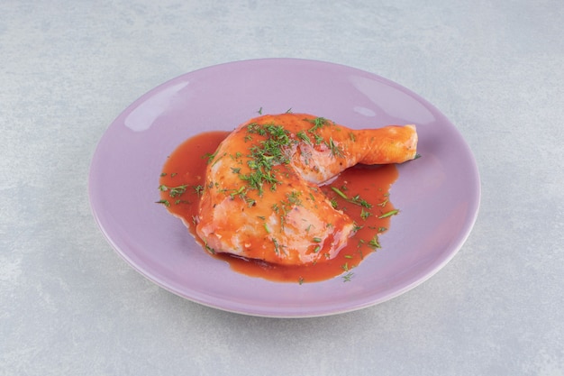 Delectable ketchup with drumstick on the plate, on the white surface