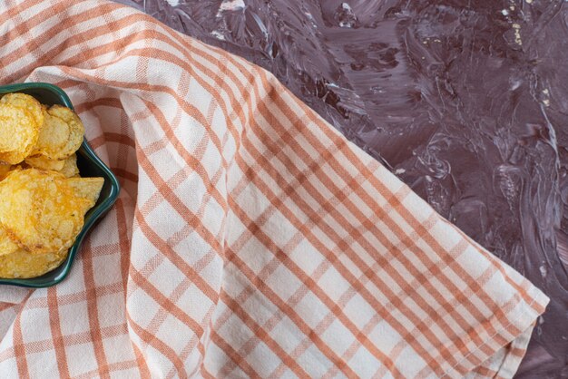 Delectable potato chips in a bowl on tea towel , on the marble table. 