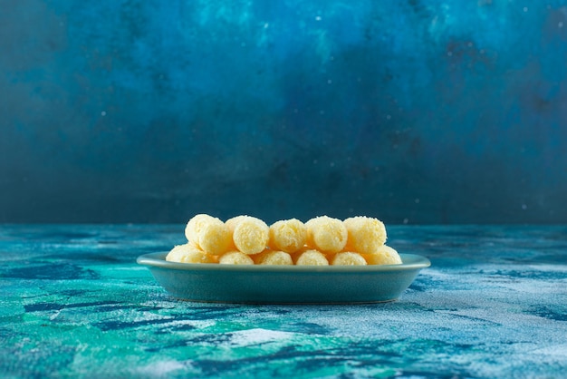 Восхитительные сладкие кукурузные палочки в тарелке на синем столе.