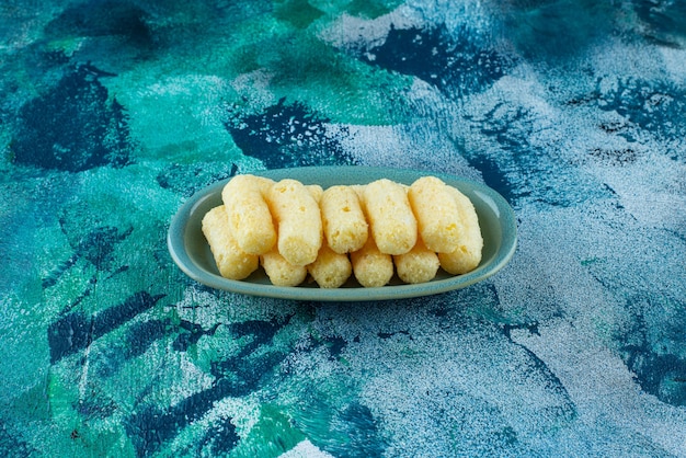 Free photo delectable sweet corn sticks in a plate on blue.