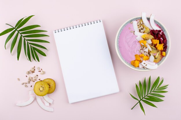 Delicious açai bowl arrangement with empty notepad