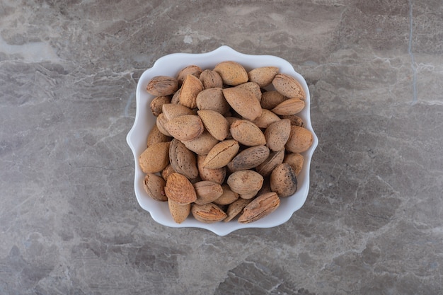 Delicious almonds in the bowl on the marble surface