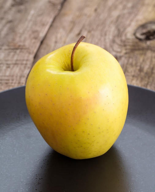 вкусное яблоко на тарелке над деревянным столом