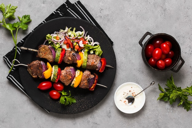 Delicious arabic fast-food skewers on black plate and tomatoes