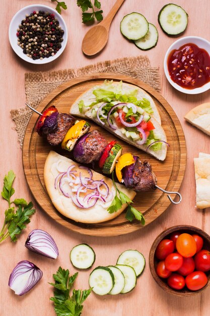 Delicious arabic fast-food veggies and meat on skewers flat lay