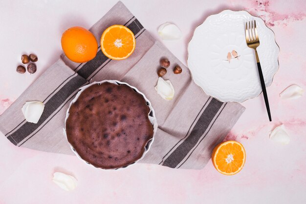 Delicious baked cake; hazelnut; citrus fruits and white petals on textured background