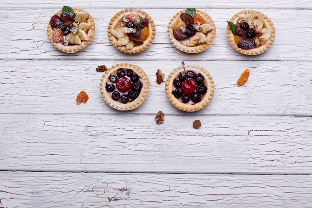 Deliziosi cestini di frutta cotti con frutti di bosco, frutta esotica, verde e noci