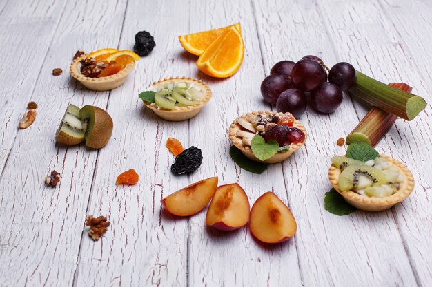 Delicious baked fruit baskets with berries, exotic fruits, greenery and nuts 