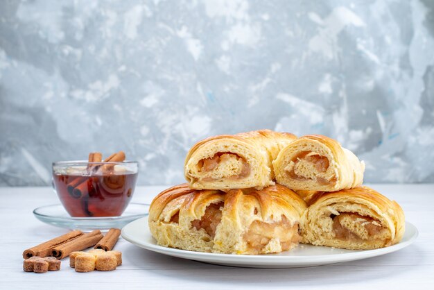 Deliziosa pasticceria al forno con ripieno dolce affettato e intero insieme a biscotti e tè sulla scrivania bianca, biscotto biscotto pasticceria torta tè dolce