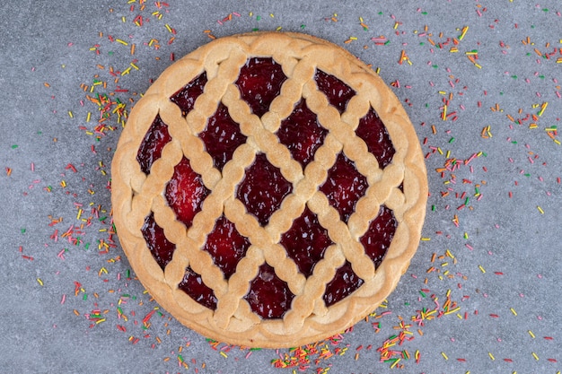 Delicious berry pie with sprinkles on marble surface