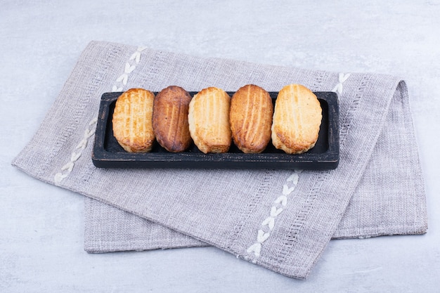 Delicious biscuits on black plate with tablecloth.