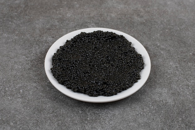 Delicious black caviar on white bowl on white plate