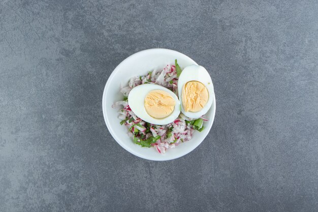 Вкусные вареные яйца и свежий салат в белой миске.
