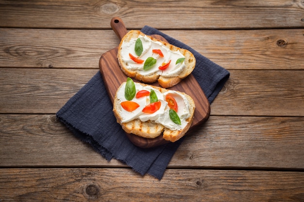 Delicious bread with cheese and tomato on a wooden background