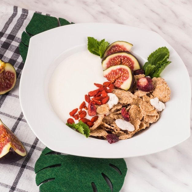 Colazione deliziosa; foglie finte di monstera e fettine di fichi con il tovagliolo di cucina su una superficie di marmo bianco