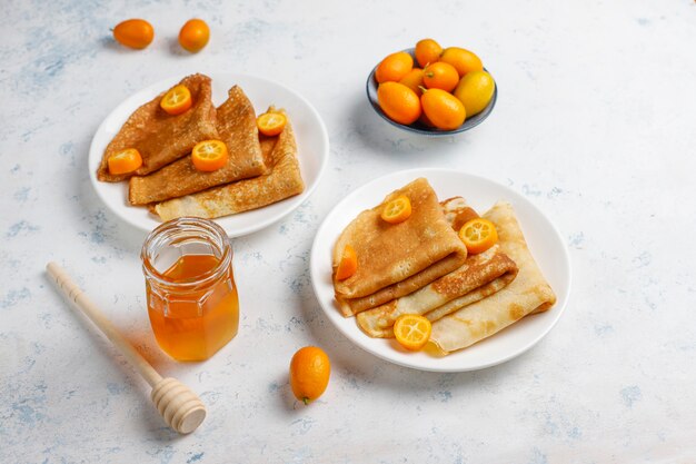 Delicious Breakfast. Orthodox holiday Maslenitsa. Crepes with cumquats and honet, top view