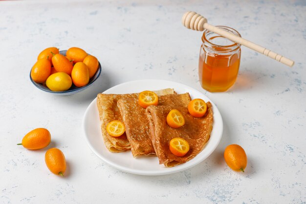 Delicious Breakfast. Orthodox holiday Maslenitsa. Crepes with cumquats and honet, top view