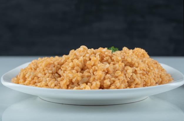 Delicious bulgur pilaf on white plate.