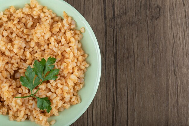 Delicious bulgur with greens on green plate.