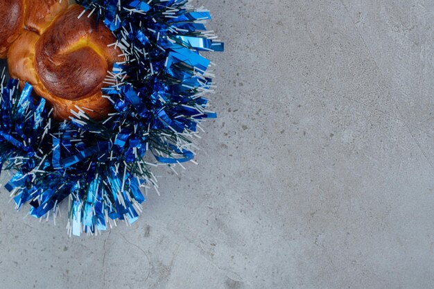 Delicious bun wrapped with blue tinsel on marble table.