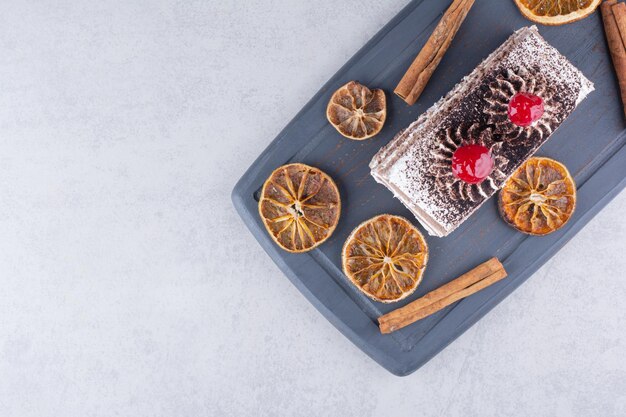 Delicious cake with cinnamons and orange slices on dark plate. High quality photo