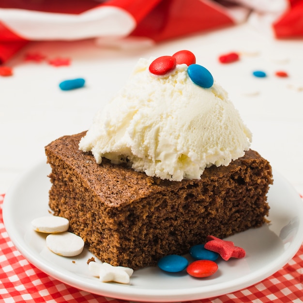 Delicious cake with ice cream scoop and candies on white plate for independence day