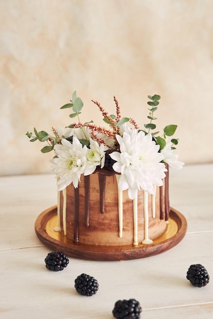 無料写真 テーブルの上に花とブラックベリーが渦巻く白と茶色のチョコレートとおいしいケーキ