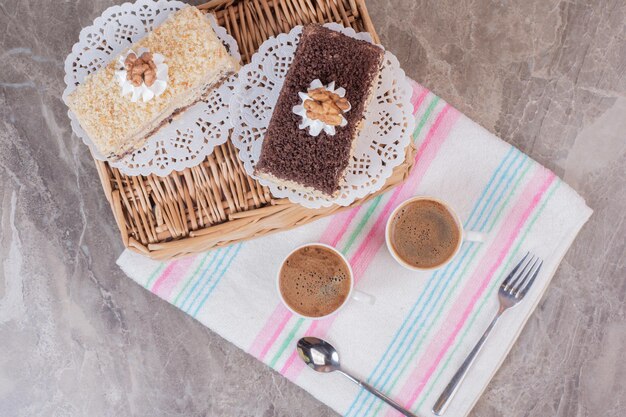 Delicious cakes and cups of coffees on tablecloth.