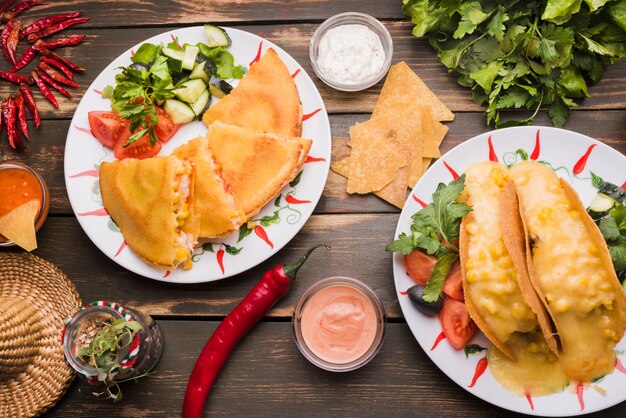 Delicious cakes near vegetable salads on plates among sauces and chili