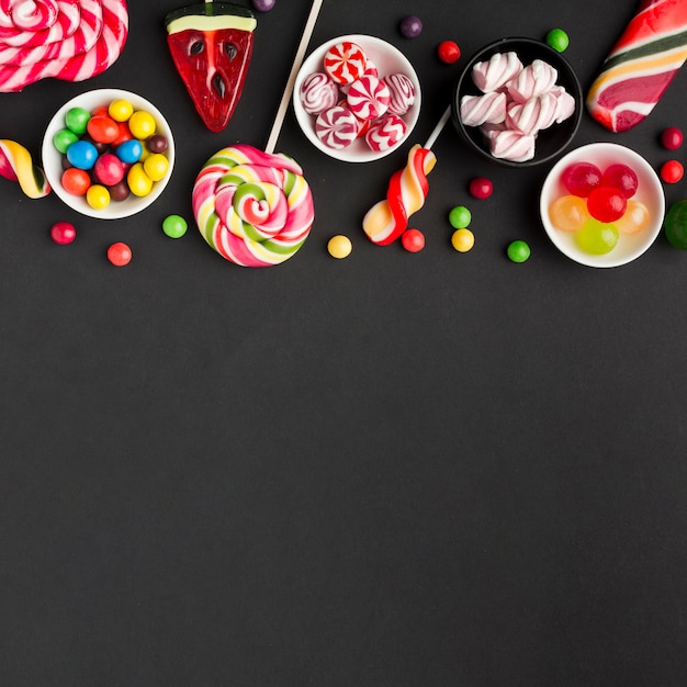 Delicious candies on black table with copy space