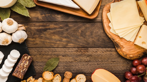 Delicious cheese with bread slice and red grapes on rustic table