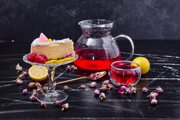 Delicious cheesecake on glass cake plate next to teapot with dried flowers. 