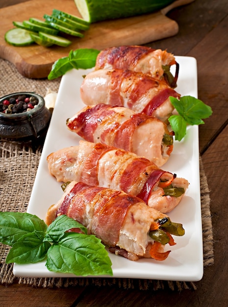 Delicious chicken rolls stuffed with green beans and carrots wrapped in strips of bacon