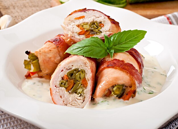 Delicious chicken rolls stuffed with green beans and carrots wrapped in strips of bacon