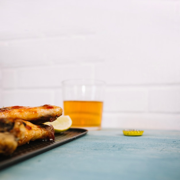 Delicious chicken wings on tray near beer