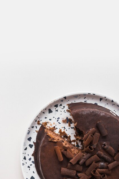 Deliziosa torta al cioccolato con fetta mancante sul piatto bianco su sfondo bianco