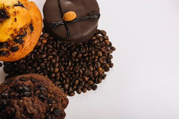 Вкусные шоколадные мини-пирожные возле кофейных зерен
