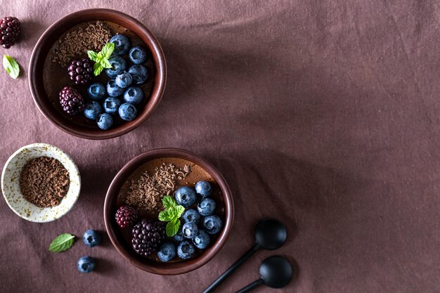 Delicious chocolate mousse or panna cotta with blueberries and blueberries on a dark fabric background