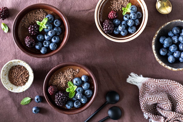 Delicious chocolate mousse or panna cotta with blueberries and blueberries on a dark fabric background