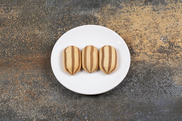 Delicious chocolate striped biscuits on white plate.