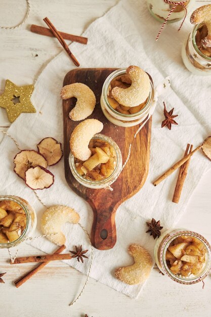 하얀 테이블에 있는 나무 접시에 구운 사과와 크림을 곁들인 맛있는 크리스마스 쿠키 디저트