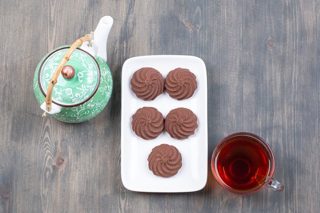 Delicious cocoa biscuits on white plate with hot tea