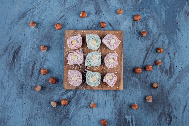 Delicious colorful sweet delights with nuts on wooden board.