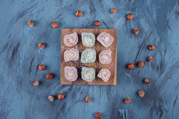 Вкусные красочные сладости с орехами на деревянной доске.