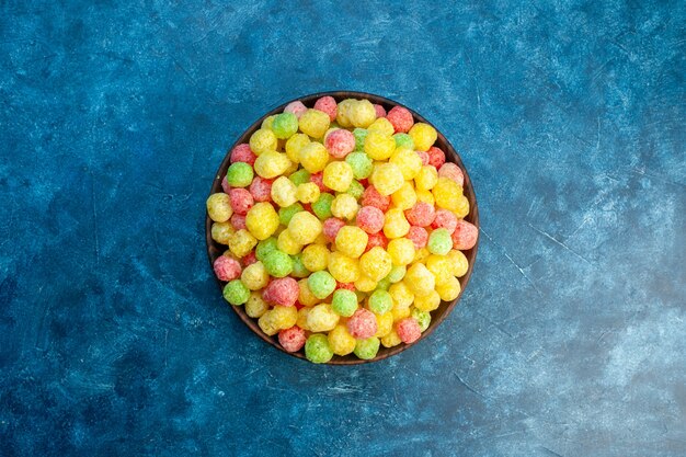 Free photo delicious coloured sweets in a small brown pot on blue background