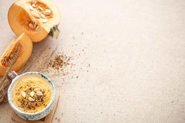 Delicious composition with pumpkin soup in a beautiful ceramic dish top view. Seasonal food.