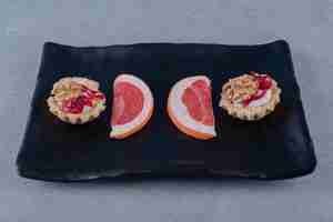 Free photo delicious cookie with grapefruit slices on black plate over grey surface