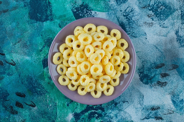 Delicious corn rings in a plate , on the blue table.