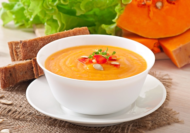 Delicious cream of pumpkin soup in a bowl on wooden table