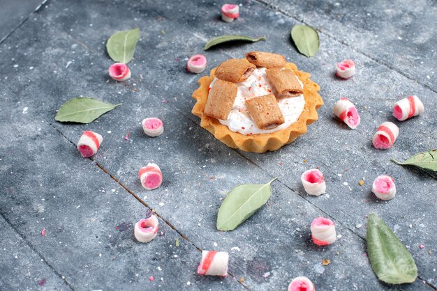 delicious creamy cake with cookies along with sliced pink candies on grey, cake sweet bake cream